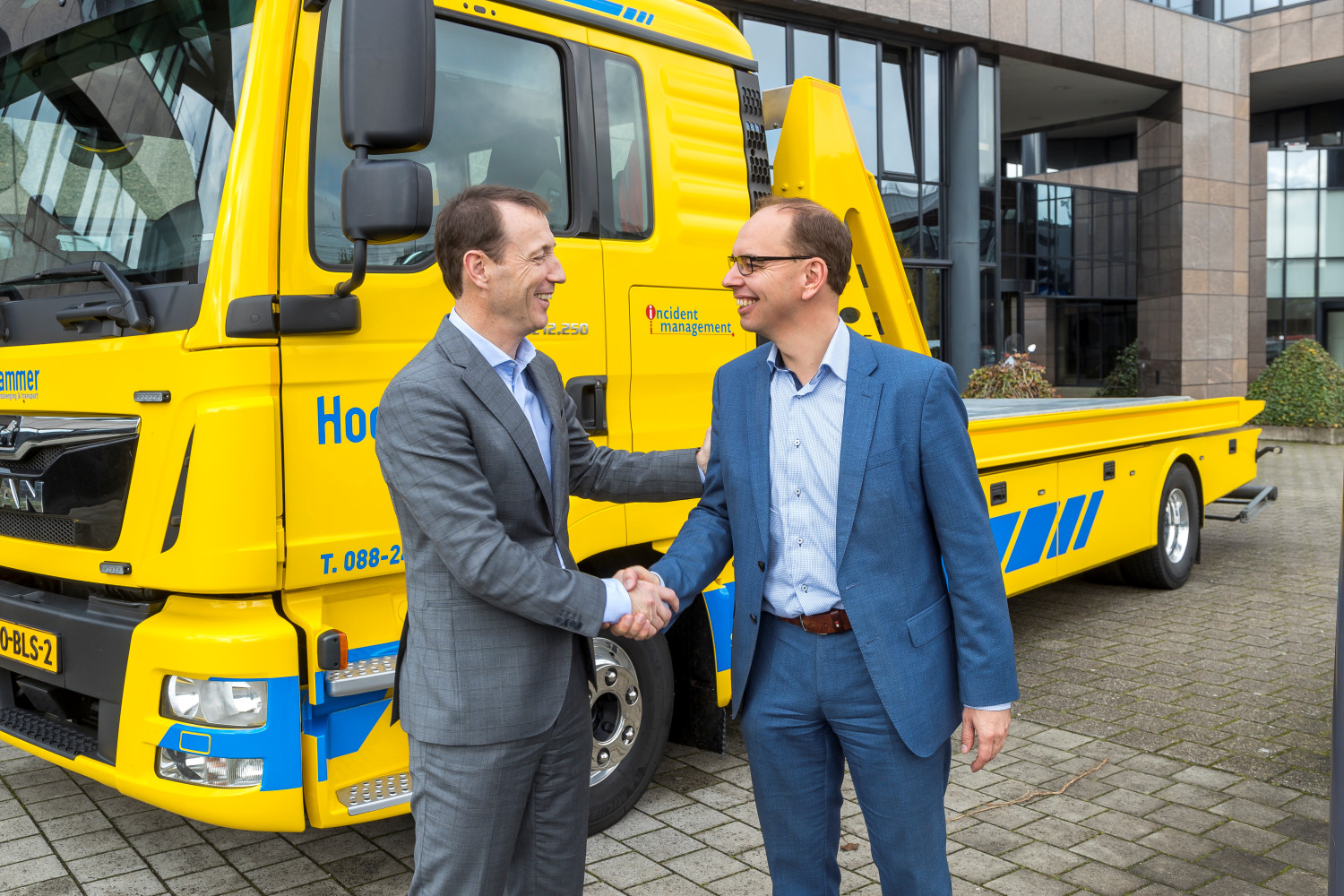 Ryan Florijn (R), chair of Stichting IMN, congratulates Hans Coffeng, managing director of CED, on the transfer of the LCM, in front of the offices of SOS International in Amsterdam-Zuidoost on 5 November 2019.