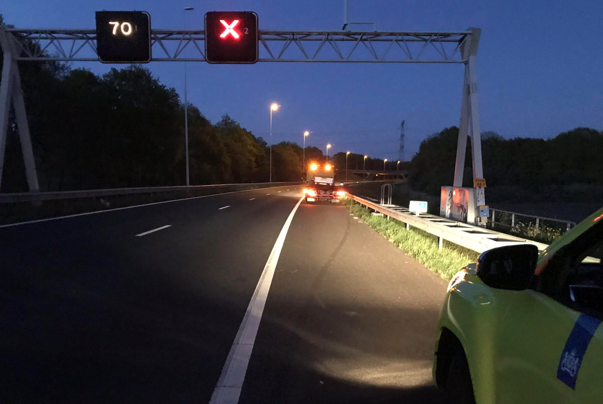 Een weginspecteur beveiligt in de avondschemering een pechverplaatsing op een zeer stille A58 bij Eindhoven op 20 april 2020